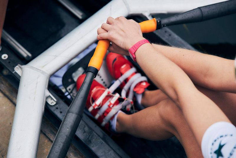 A close-up shows a rower's feet positioning and arms from above. 