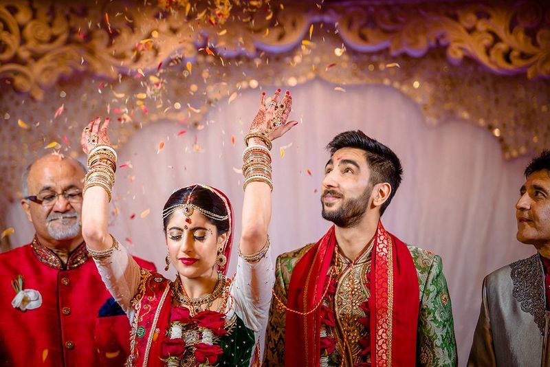 A bride throws her arms up and her new husband looks up.