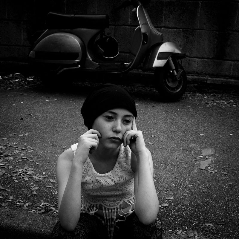 A young girl sits waiting for her parents to pick her up after attending a photography workshop.