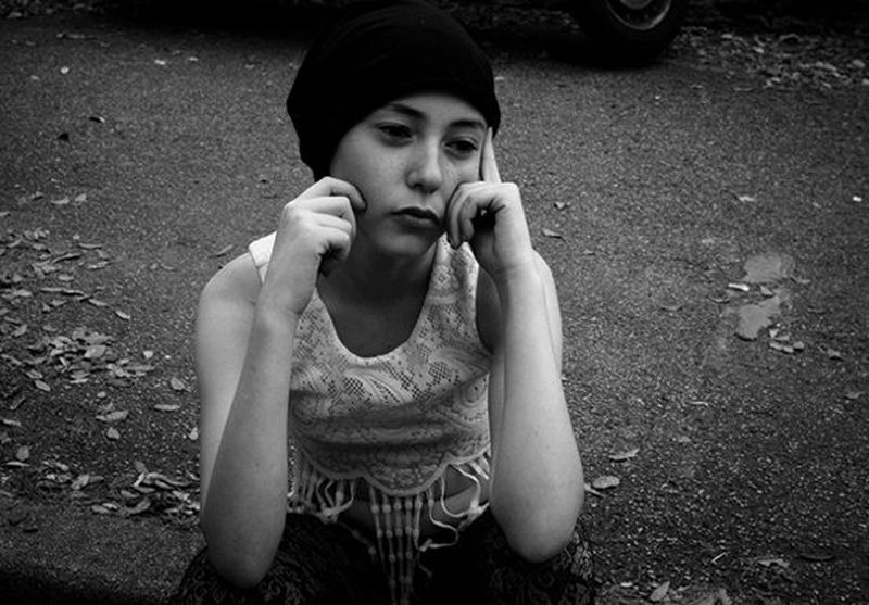 A young girl sits waiting for her parents to pick her up after attending a photography workshop.