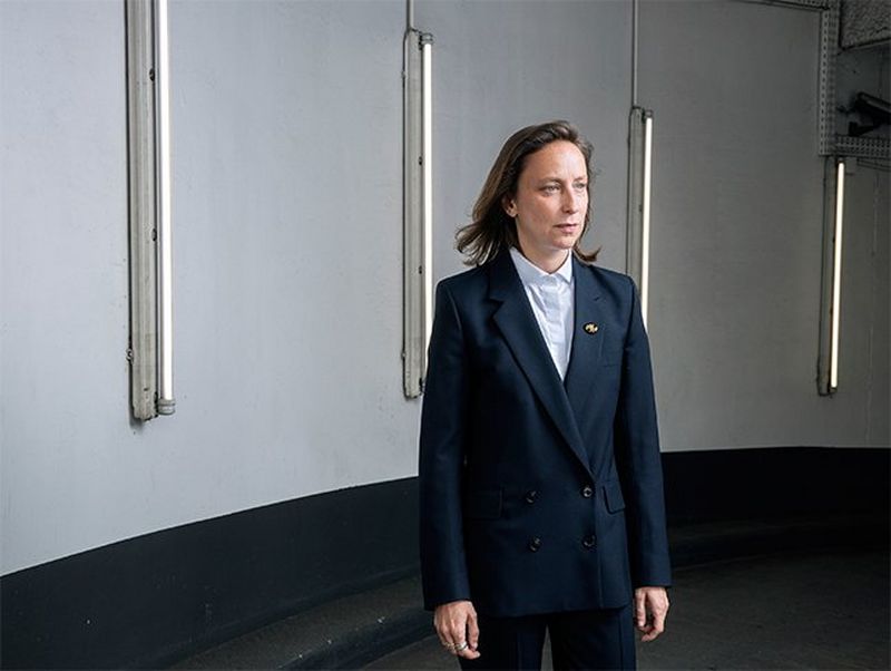 Writer and director Céline Sciamma pictured against a curved concrete wall with vertical strip lights. Photograph by Paolo Verzone on a Canon EOS R.