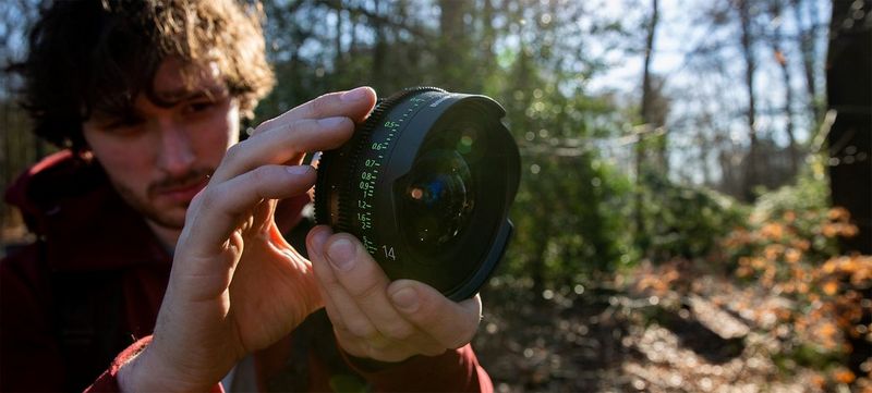 Filmmaker Freek Wonderland holds up a Canon CN-E14mm T3.1 FP X Sumire Prime lens.