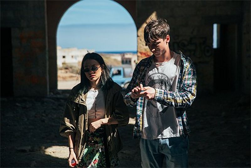 A couple stand in an abandoned chapel with deep shadows and bright highlights.