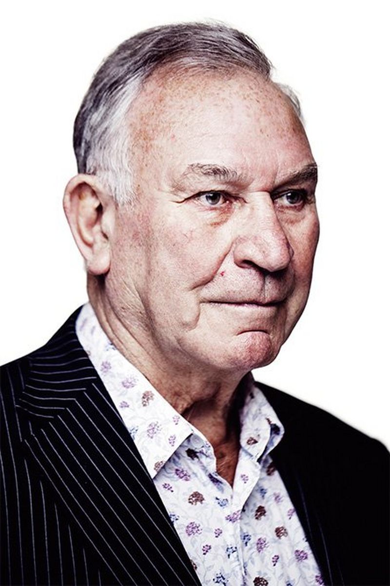 Three-quarter-view portrait photo of a middle-aged man wearing a dark pin-striped jacket and an open-necked shirt