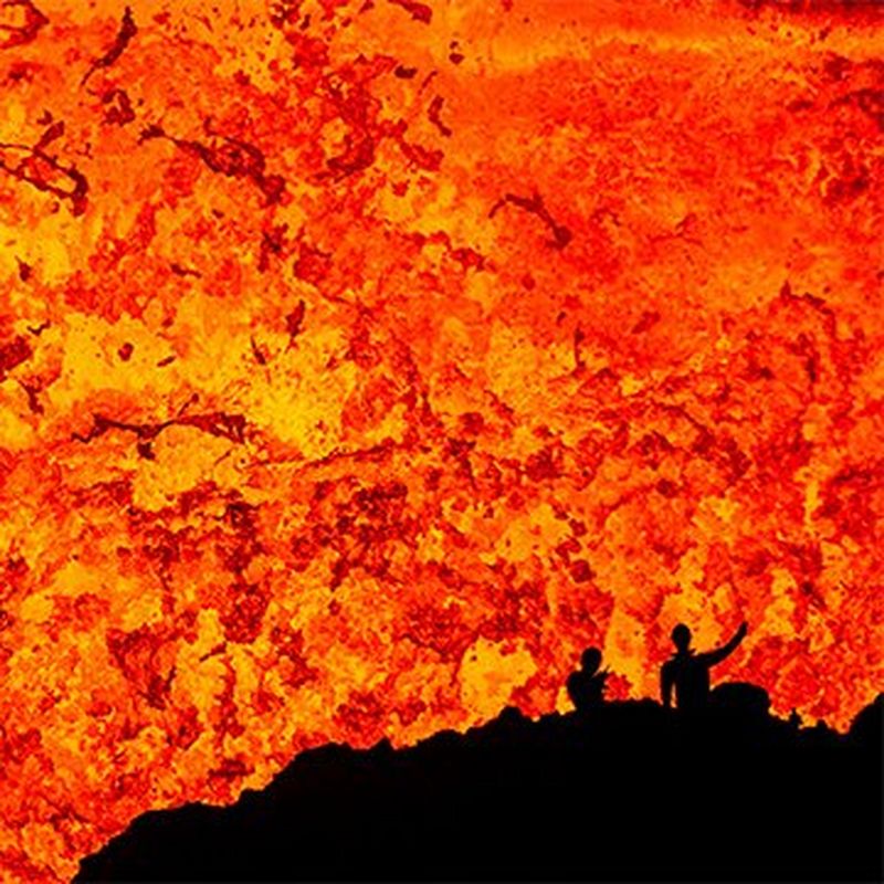 Two scientists silhouetted against the lava lake inside the Benbow crater on the volcanic island of Ambrym.