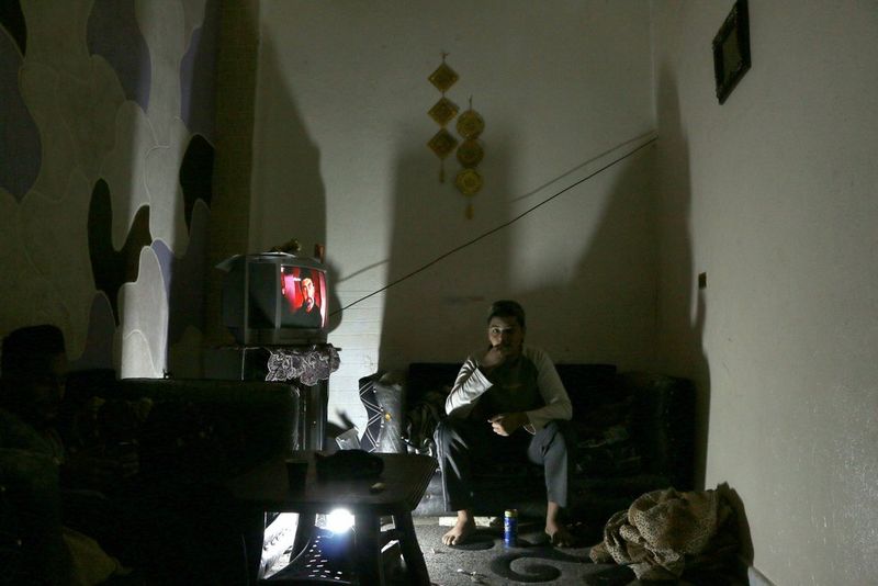 A project participant&#39;s image, showing a man sitting in semi-darkness watching television, to illustrate the boredom experienced within the camp. 