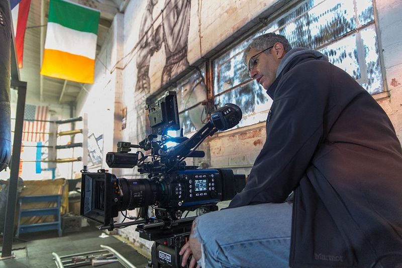A camera operator with a Canon EOS C700 FF filming in a boxing gym.