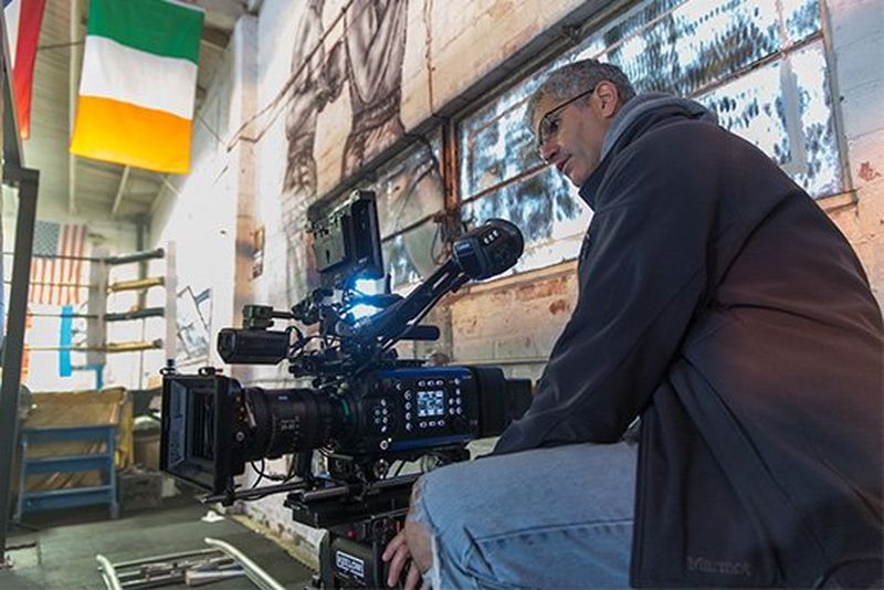 A camera operator with a Canon EOS C700 FF filming in a boxing gym.