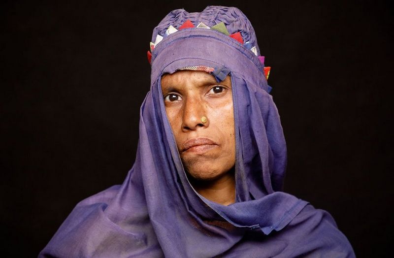 A woman wears a purple headscarf decorated with colourful triangles.