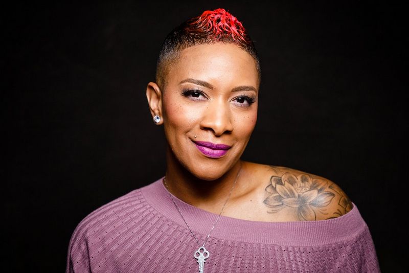 A woman wears a silken headscarf with brown, green and red floral patterns.