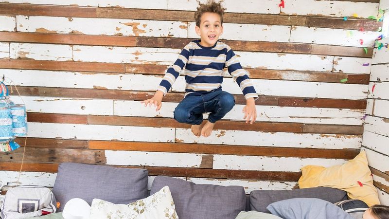 Boy jumping on a sofa shot using the Canon Speedlite EL-100