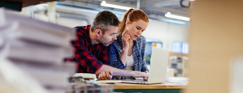 A woman talks at a meeting with five other colleagues around a desk