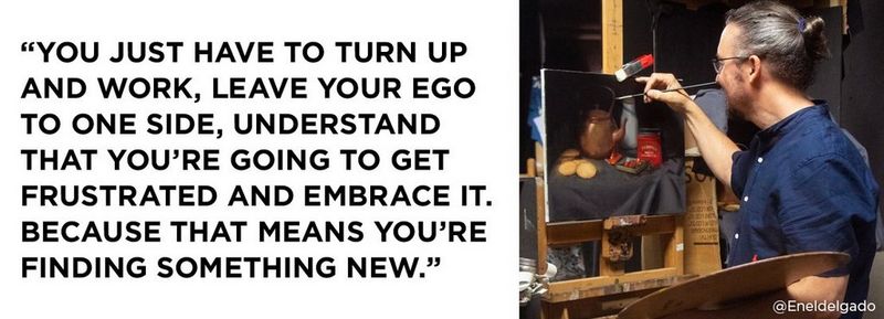 Right: Connell stands facing his wooden easel, a raised paintbrush in his right hand and large wooden palette resting on his right hand. He is painting a still life, which is secured to the easel with a red clip at the top. He wears a blue shirt and glasses, with his hair in a bun, midway up the back of his head. On the left is a quote that reads: “You just have to turn up and work, leave your ego to one side, understand that you’re going to get frustrated and embrace it. Because that means you’re finding something new.” © @Enelgado