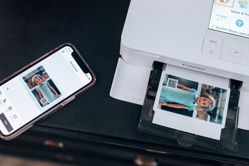 A white Canon SELPHY CP1500 printer printing an image of a young girl in school uniform. The image also contains a small QR code.