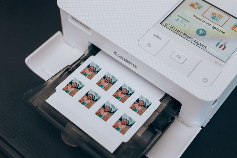 A white Canon printer prints out a small sheet of paper with the same image of a young girl repeated eight times.