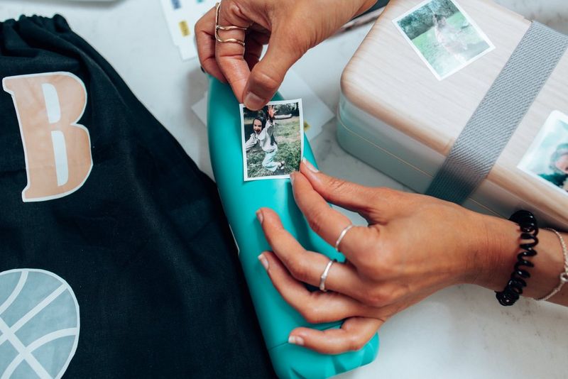 Dvije ruke koje pažljivo lijepe naljepnicu s djevojčicom na zelenu bocu za vodu.