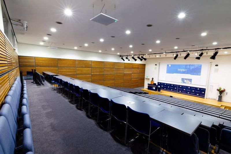 A large lecture hall with tiered seating, with a Canon CR-N350 PTZ camera affixed to the ceiling at the back.