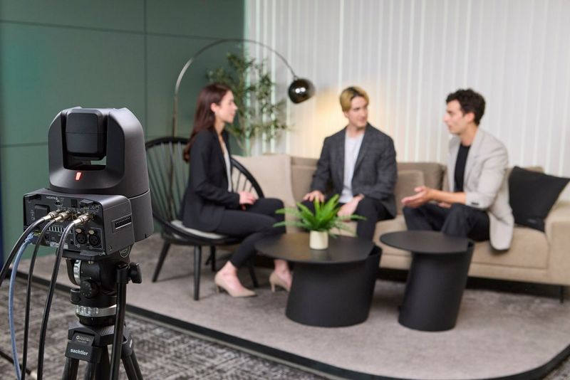 A Canon CR-N400 PTZ camera records three people conducting an interview on a settee.