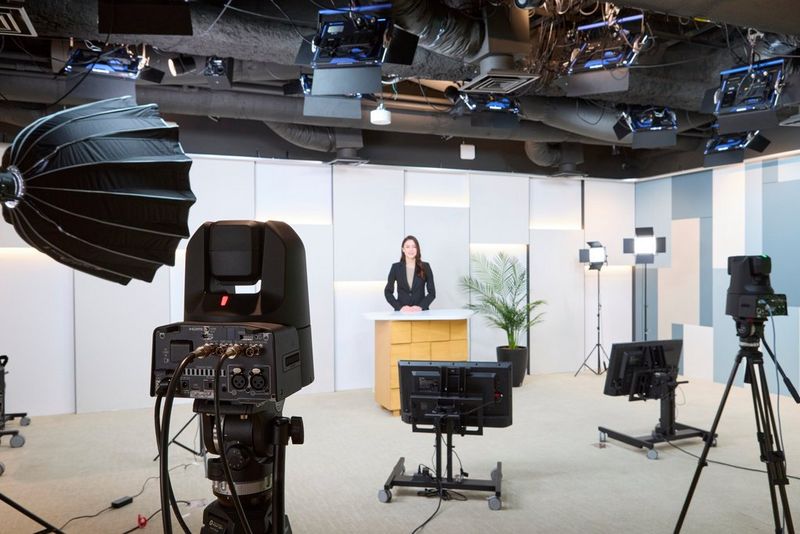 Two Canon CR-N400 PTZ cameras pointed towards a presenter standing behind a desk in a studio setting.