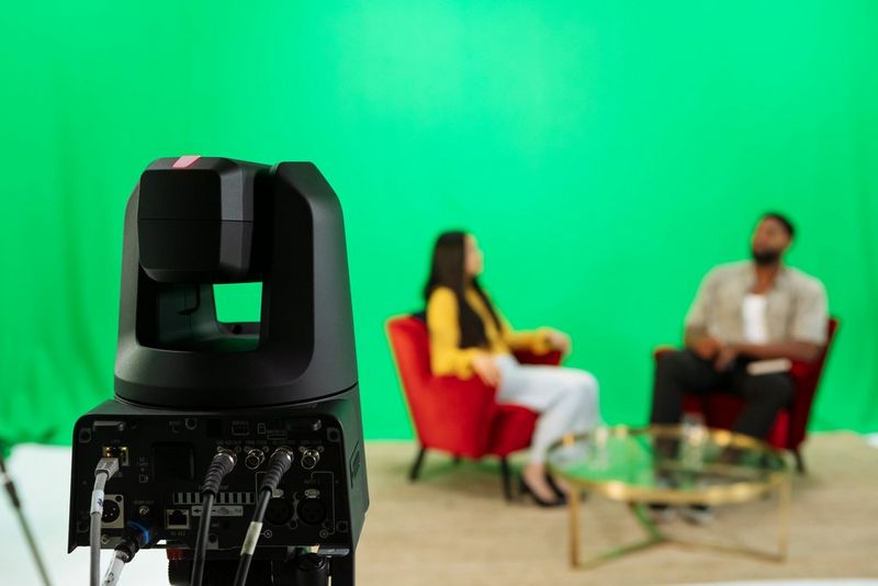 A Canon CR-N700 PTZ camera filming two people sat in facing armchairs.