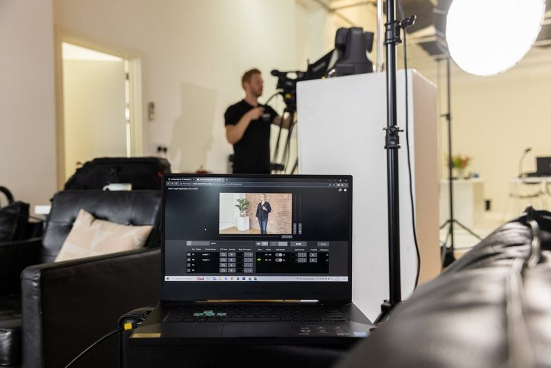 מסך מחשב נייד מציג את היישום Auto Loop שבשימוש בזמן שברקע יש אדם שמתפעל את Canon XF605.