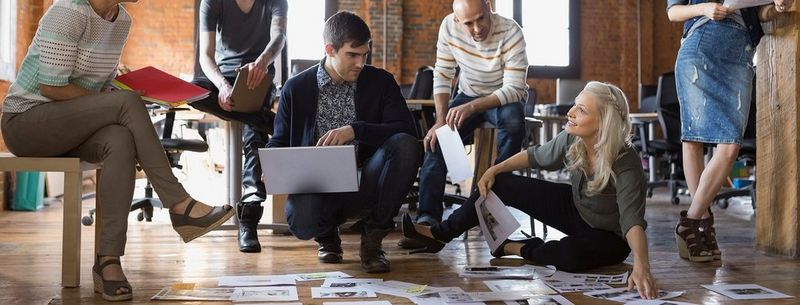 creative-team-reviewing-prints-on-floor-of-office