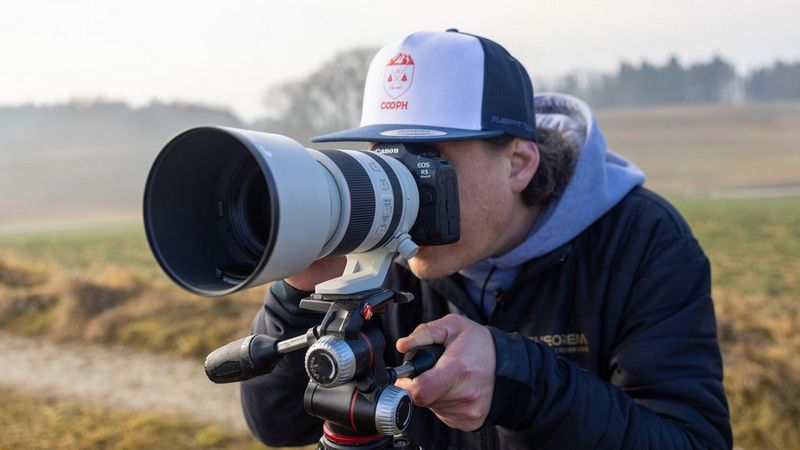 Action photographer Lorenz Holder presses his eye to the viewfinder of his Canon EOS R5 Mark II mirrorless camera.