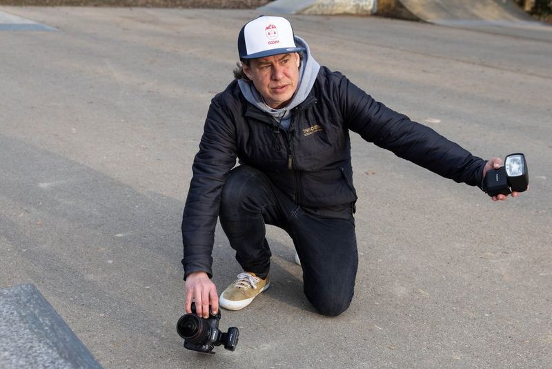 Photographer Lorenz Holder positions his Canon EOS R5 Mark II camera low to the ground and holds a Speedlite EL-5 flash at arm’s length in his other hand, ready for an action photograph of a skateboarder.
