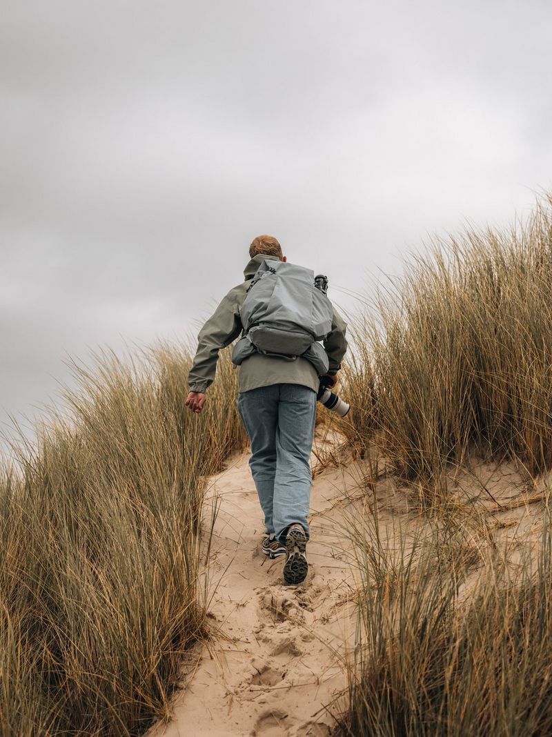 Travel photographer Cuno de Bruin walks up a sand dune wearing a backpack and carrying his Canon EOS R5 Mark II camera.