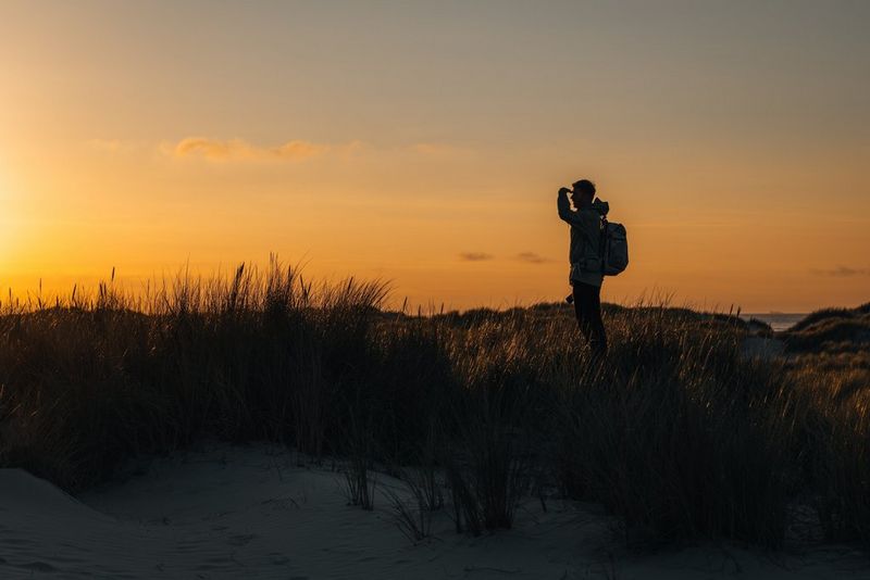 Dutch travel photographer Cuno de Bruin silhouetted at sunset on a sand dune.