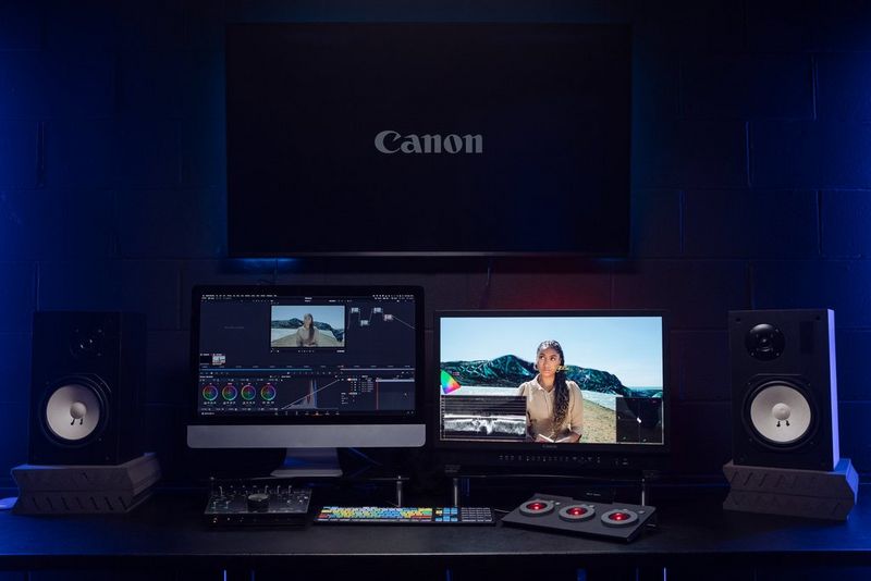 A desk is set up with two monitors, a keyboard, speakers and video editing equipment.