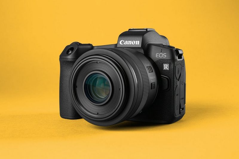 Eine Canon EOS R spiegellose Kamera mit angebrachtem Objektiv vor einem gelben Hintergrund