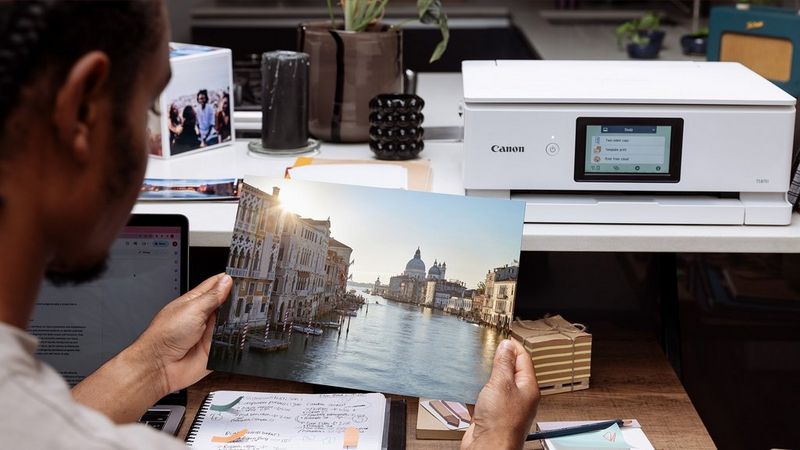 Ein PIXMA Drucker produziert langlebige Fotodrucke; eine Person hält ein lebhaftes Bild von Venedig.