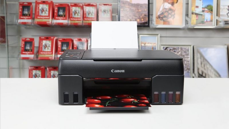 Canon PIXMA G650 Drucker beim Drucken eines Fotos im Geschäft mit Canon Papierpackungen.