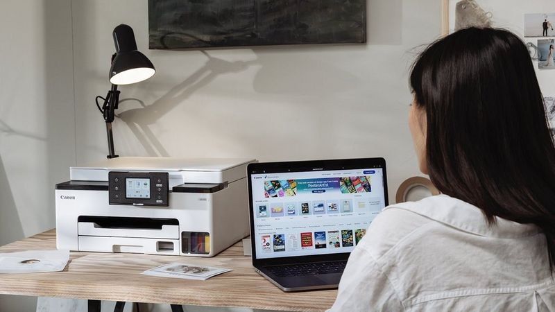 Person, die im Homeoffice einen Canon MAXIFY GX1015-Drucker mit Laptop verwendet.