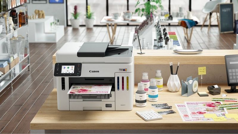 Canon MAXIFY GX7150 Drucker in kreativem Arbeitsbereich beim Drucken bunter Materialien neben Bastelzubehör.