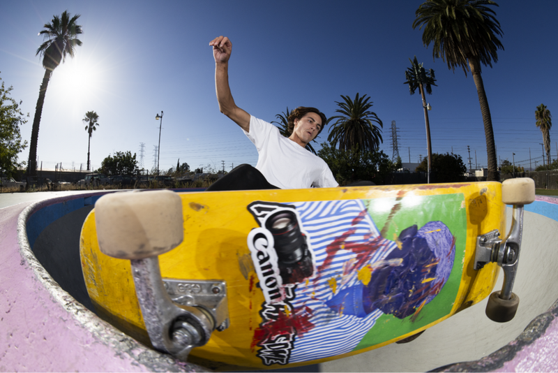 Fisheye-Aufnahme eines Skateboarders, der entlang einer geschwungenen Betonstruktur fährt.