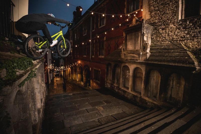 Un rider salta da un muro in un vicolo lastricato e una raffica di luci del flash lo immortala nel bel mezzo del salto.