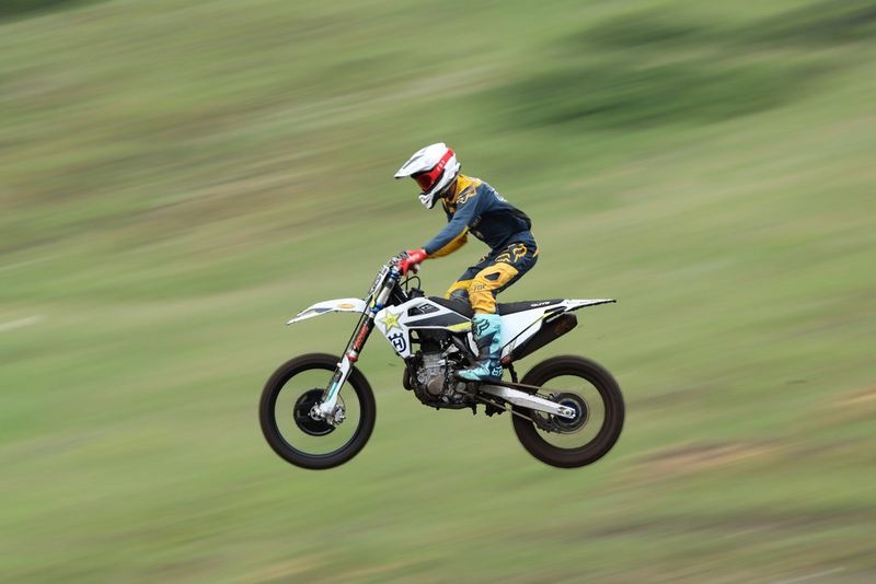 Райдер быстро едет на мотоцикле по полю.