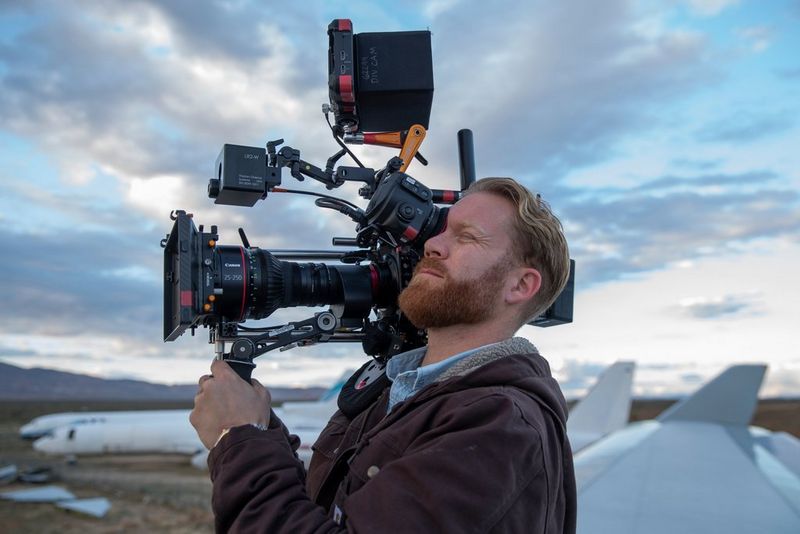 Le cinéaste Steve Holleran filmant avec la caméra Canon EOS C300 Mark III sur l'aile d'un avion, avec d'autres appareils en arrière-plan.