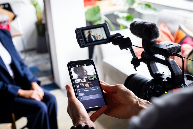 Sarah Thomas Moffat houdt een smartphone vast met daarop de Canon Multi-Camera Control-app, met een EOS C400 op de achtergrond.