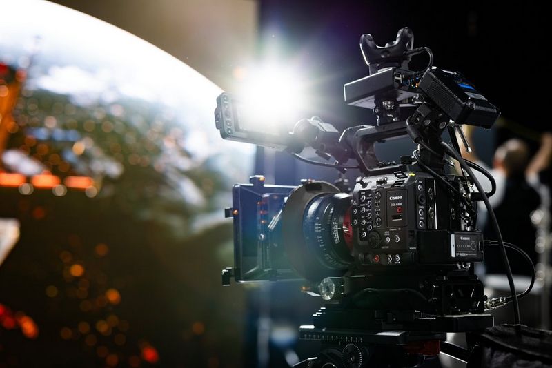 A Canon EOS C400 cinema camera on a virtual production set with lens flare off the LCD screen, with a virtual screen in the background.