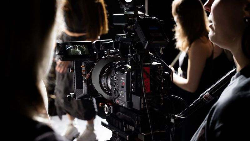 A view from behind of a Canon EOS C400 in use on a shoot, with a camera operator and other crew members also in shot.