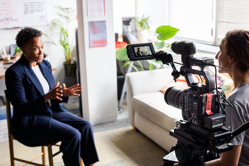 Beverley De-Gale OBE zit op een stoel en praat één-op-één met Sarah Thomas Moffat, die een Canon EOS C400 heeft.