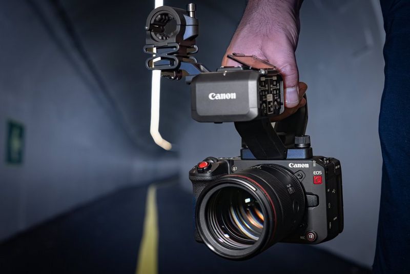 A man in a tunnel holds the Canon EOS C50 camera by its top handle.