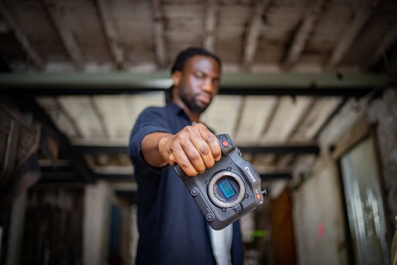 Мужчина вытянул руку и держит камеру Canon EOS C70 без объектива.