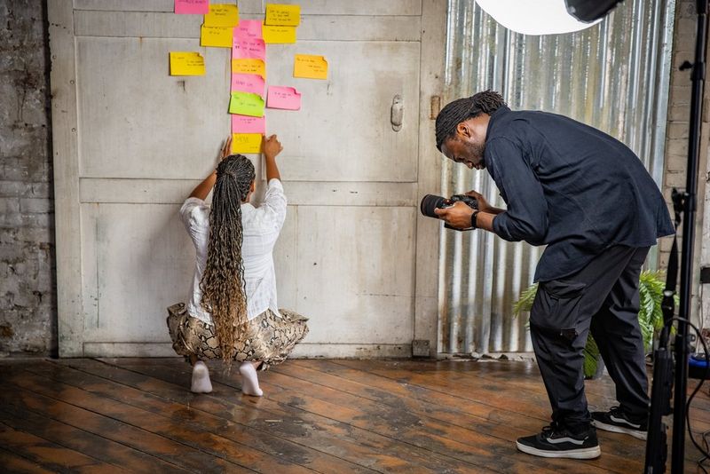 Jolade Olusanya films a woman sticking multi-coloured notes to a wall.