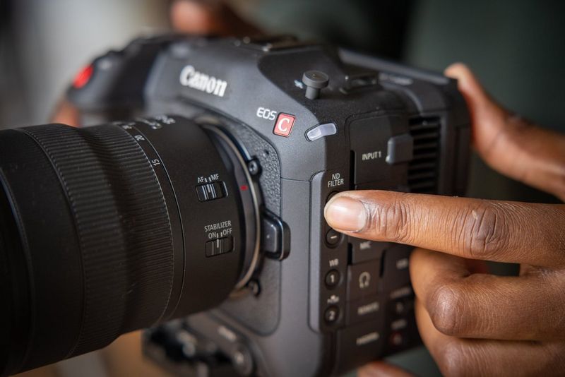 Een vinger die op de knop voor het ND-filter drukt aan de zijkant van een Canon EOS C70-videocamera.