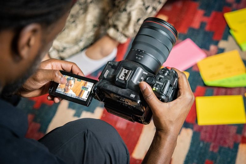Мужчина смотрит на сенсорный экран с регулируемым углом наклона камеры Canon EOS C70, на которую установлен объектив Canon RF 15-35mm F2.8L IS USM.