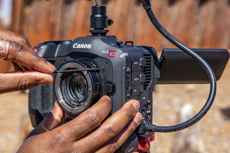 A Canon Mount Adapter EF-EOS R 0.71x being attached to a Canon EOS C70 camera.